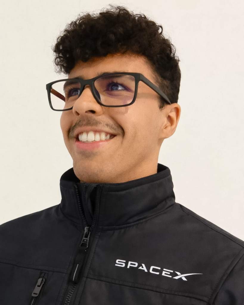 Simon, o fundador do Multiverso Corporation vestindo uma jaqueta preta e moderna da companhia aeroespacial americana, SpaceX.
